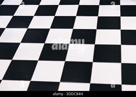 Checkered floor pattern with black and white tiles creating a geometric, abstract background with strong perspective Stock Photo