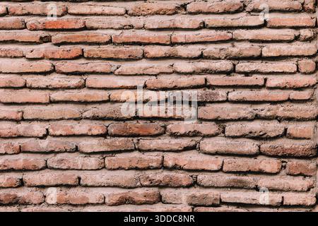 Weathered rough masonry wall forming a textured background, showing aged and cracked bricks with visible mortar Stock Photo