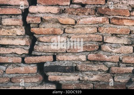 Old brick wall with a large vertical crack displaying textured weathered surfaces and the process of decay Stock Photo
