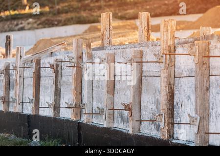 Concrete foundation formwork forming a new building base at a residential construction site, showing wood boards and metal rebar Stock Photo
