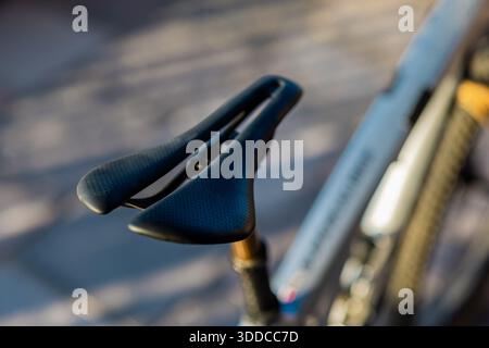 A close-up, shallow-depth-of-field shot of a sleek, black aerodynamic bicycle saddle mounted on a high-performance mountain bike, featuring a central Stock Photo