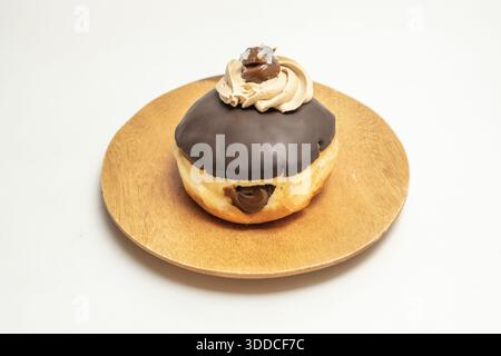 A chocolate Berliner with a soft brioche dough, filled with milk chocolate ganache and covered with a glossy chocolate fondant glaze Stock Photo
