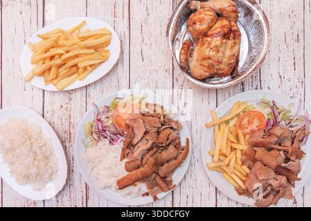 Beef kebab with yogurt and garlic sauce, served with a side of French fries and a tomato and cucumber salad. Stock Photo
