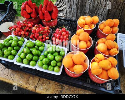 Peaches, plums, apricots, strawberries on white plastic plates for sale. Stock Photo