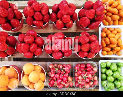 Peaches, plums, apricots, strawberries on white plastic plates for sale. Stock Photo