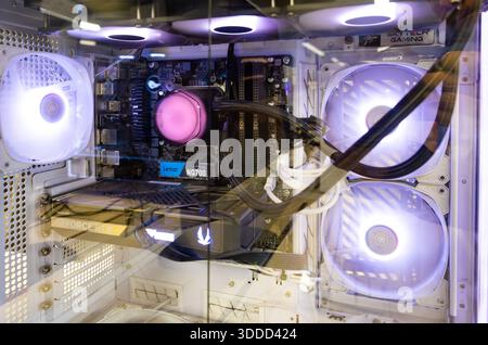 Interior of modern gaming PC with RGB liquid cooling system, illuminated fans, graphics card and motherboard visible through tempered glass side panel Stock Photo