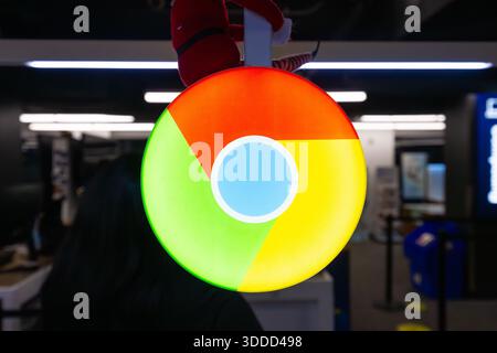Google Chrome browser logo displayed on illuminated circular sign inside a modern public interior, representing internet brand Stock Photo