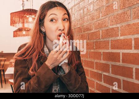 Young woman, cleaning her mouth with a napkin and looking sideways Stock Photo