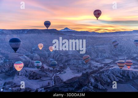 Shortly before sunrise behind the Erciyes Dağı volcano, hot air balloons float over the tuff landscape of Cappadocia. Göreme, Central Anatolia Region, Turkey Stock Photo