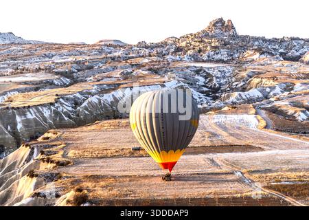 Sultanballoons hot air balloon flies over the snow-covered landscape of Göreme, Central Anatolia Region, Turkey Stock Photo