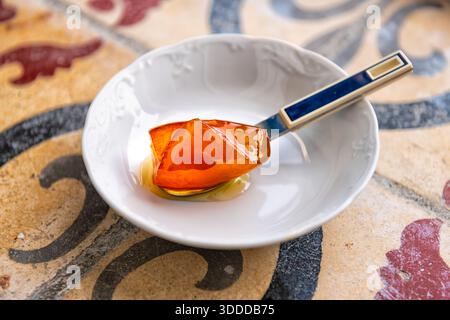 Spoon sweet traditional Greek dessert in sugar syrup, bitter orange preserve on white plate with spoon from Ikaria island, Greece longevity blue zone Stock Photo