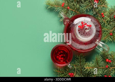 Glass cup and teapot of hot viburnum tea with fir branches on green background Stock Photo