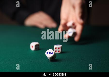 Man throwing white game dices on green table, closeup Stock Photo