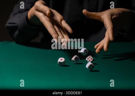 Man throwing white game dices on green table, closeup Stock Photo