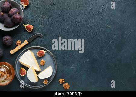 Plate with tasty Camembert cheese, fresh ripe figs and walnuts on blue grunge background Stock Photo
