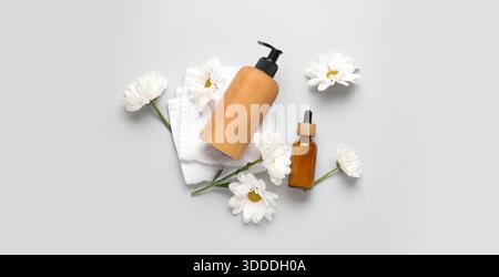 Cosmetic products, towel and chamomiles on light background Stock Photo