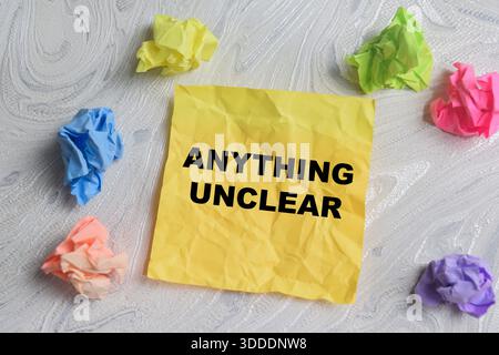 Concept of anything unclear write on sticky notes isolated on Wooden Table. Stock Photo