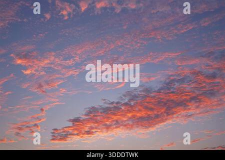 The sunset sky filled with vibrant clouds with its colors range from soft pinks to fiery oranges, creating a beautiful atmosphere Stock Photo