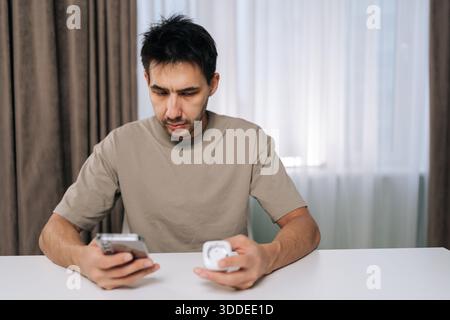 Man connecting smart home device using smartphone, looking at application settings, setting up and controlling smart socket from mobile app, exploring Stock Photo