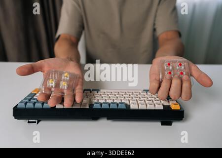 Man holding mechanical keyboard switches, choosing between different types for custom keyboard building and maintenance, repairing personal computer Stock Photo