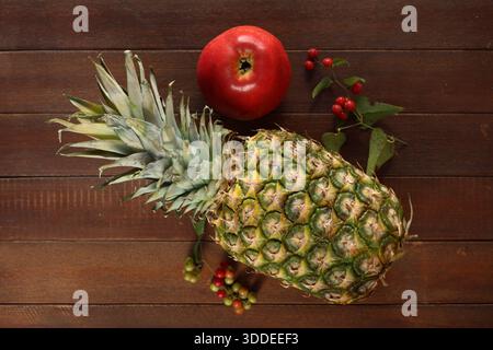 Close-up of a Whole Fresh Pineapple and Red Apple Resting on a Rustic Wooden Table Surface Stock Photo