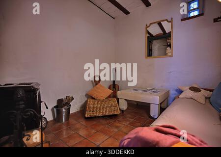 Cozy rustic living room with wicker chair guitar table and sofa in warm homey setting Stock Photo
