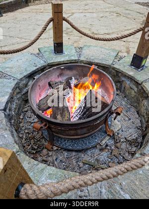 Outdoor Fire Pit with Burning Logs in Stone Surround, England Stock Photo