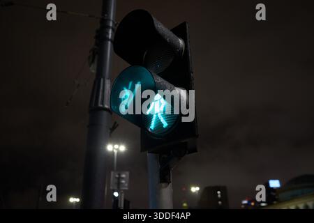Green pedestrian traffic light glowing at night in Warsaw, Poland, during winter conditions. Stock Photo