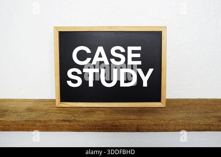 Case Study text written on blackboard with wooden shelf and concrete background Stock Photo