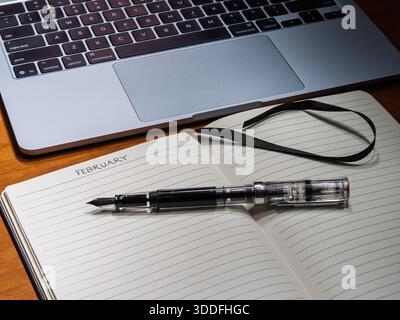 Setting February intentions in an analog journal juxtaposed with a digital keyboard for modern workflow and organization. Stock Photo
