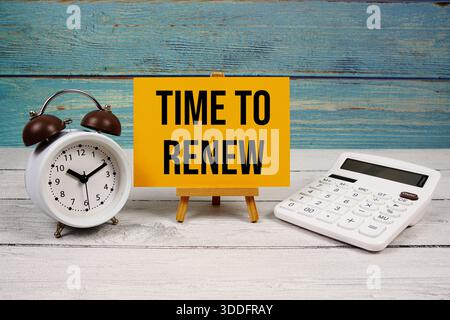 Time To Renew text written on paper card with calculator and alarm clock on wooden background Stock Photo