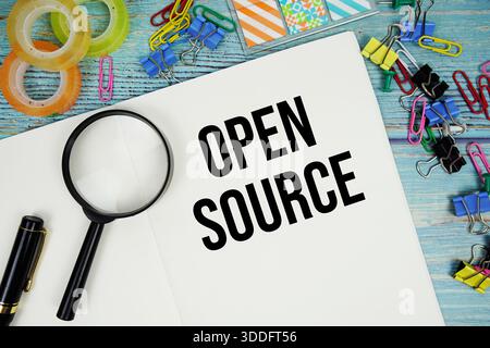 Open Source text written on notepad with alarm clock and magnifying glass flat lay on wooden background Stock Photo