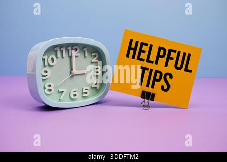 Helpful Tips text and alarm clock on blue and purple background Stock Photo