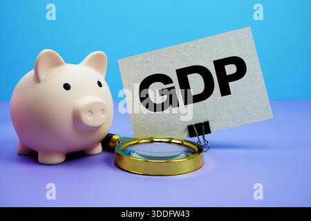 GDP text with piggy bank and magnifying glass on blue and purple background Stock Photo