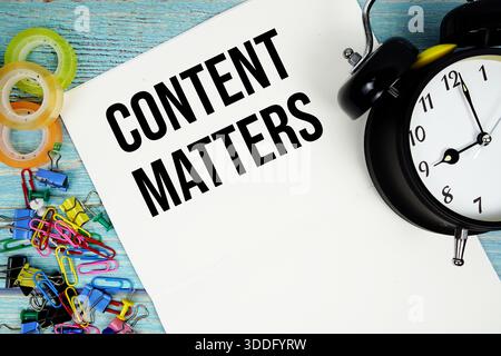 Content Matters text with alarm clock and colorful office supplies on a blue wooden surface Stock Photo