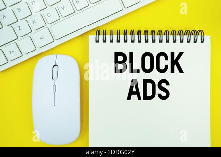 Notepad with the text "Block Ads" with white keyboard and wireless mouse on yellow background Stock Photo