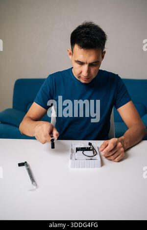 Vertical portrait of technician male assembling wi-fi module using tools at home office desk, focusing on intricate components and ensuring proper Stock Photo