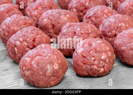 Raw homemade beef meatballs prepared on a wooden cutting board background. Stock Photo