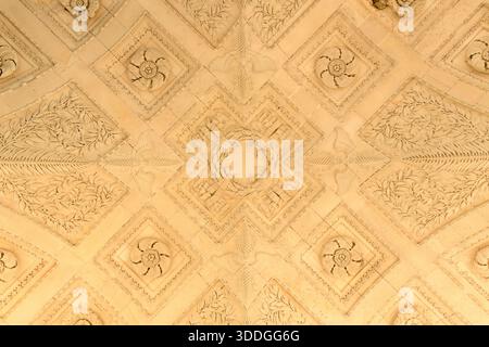 Ornate ceiling of the Arc de Triomphe du Carrousel in Paris featuring intricate floral motifs and geometric bas-reliefs illuminated by warm natural light. Stock Photo