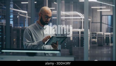 On Site Coordination, IT Specialist Using Tablet to Diagnose Rack Status. Focused IT Professional Diagnoses Server Rack Status Using Mobile Tablet Device. Coordination and On Site Troubleshooting. Stock Photo