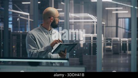 On Site Coordination, IT Specialist Using Tablet to Diagnose Rack Status. Focused IT Professional Diagnoses Server Rack Status Using Mobile Tablet Device. Coordination and On Site Troubleshooting. Stock Photo