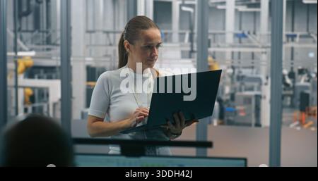 Woman Monitoring Automated Systems on Laptop. Technical Specialist Using Laptop Check or Diagnose Automated Industrial Systems. Real Time System Monitoring, on Site Diagnostics, Process Optimization. Stock Photo