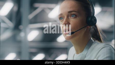 Close Up of Professional Adult Woman Wearing Headset While Communicating With Colleague IT Engineers. Concept of Concentration and Role in Modern, Sophisticated Technical Environment. Portrait. Stock Photo