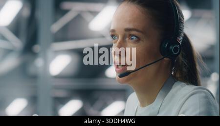 Close Up of Professional Adult Woman Wearing Headset While Communicating With Colleague IT Engineers. Concept of Concentration and Role in Modern, Sophisticated Technical Environment. Portrait. Stock Photo
