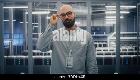 Technical Expert With Warm, Professional Expression in Blue Lit Environment Sand Metal Structures of Data Center Control Room. Technical Competency and Positive Professional Attitude. Portrait. Stock Photo
