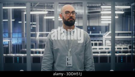 Technical Expert With Warm, Professional Expression in Blue Lit Environment Sand Metal Structures of Data Center Control Room. Technical Competency and Positive Professional Attitude. Portrait. Stock Photo