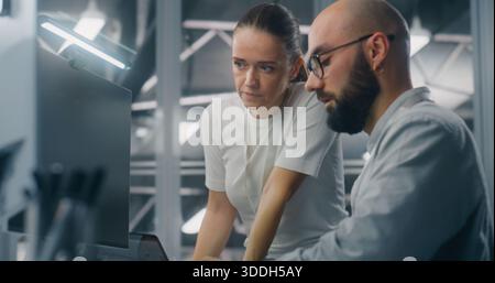Engineers Reviewing Network Performance Data. Male and Female IT Engineer Team Collaborating Over Computer Monitor to Review Critical Network Performance Metrics. Teamwork and Real Time IT Monitoring. Stock Photo