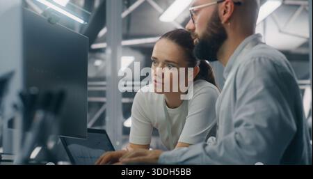 Engineers Reviewing Network Performance Data. Male and Female IT Engineer Team Collaborating Over Computer Monitor to Review Critical Network Performance Metrics. Teamwork and Real Time IT Monitoring. Stock Photo