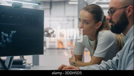 Team of Specialists Utilizing Multi Screen Workstation For Digital Twin. Young Technicians Analyzes Work Robotic Equipment on Multi Screen Setup, Utilizing Digital Twin Optimize Factory Operations. Stock Photo