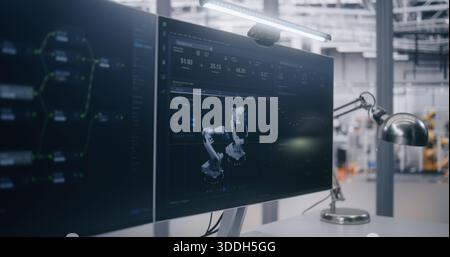 Computers on Desk Display Technical Data and Graphs With Digital Model of Robotic System. Factory Floor and Robotic Arms Visible in Background. Concept of Automation and Control System Monitoring. Stock Photo